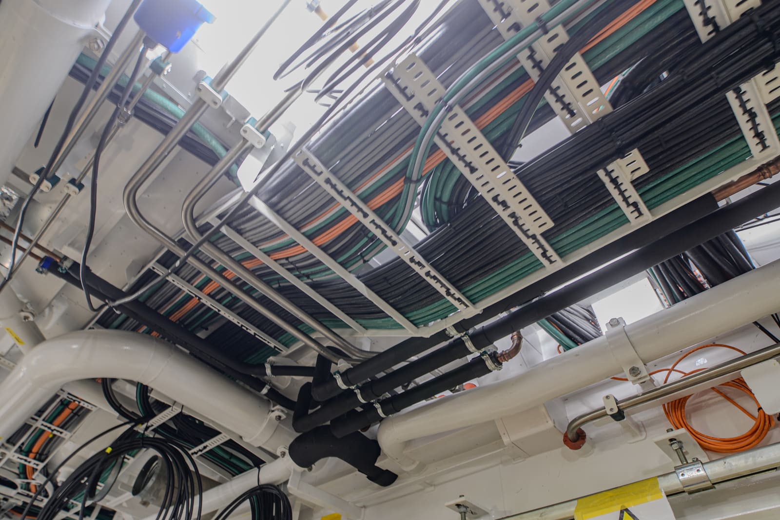 Multi-tier cable trays carrying colour-coded marine power and signal cables across a vessel engine room overhead
