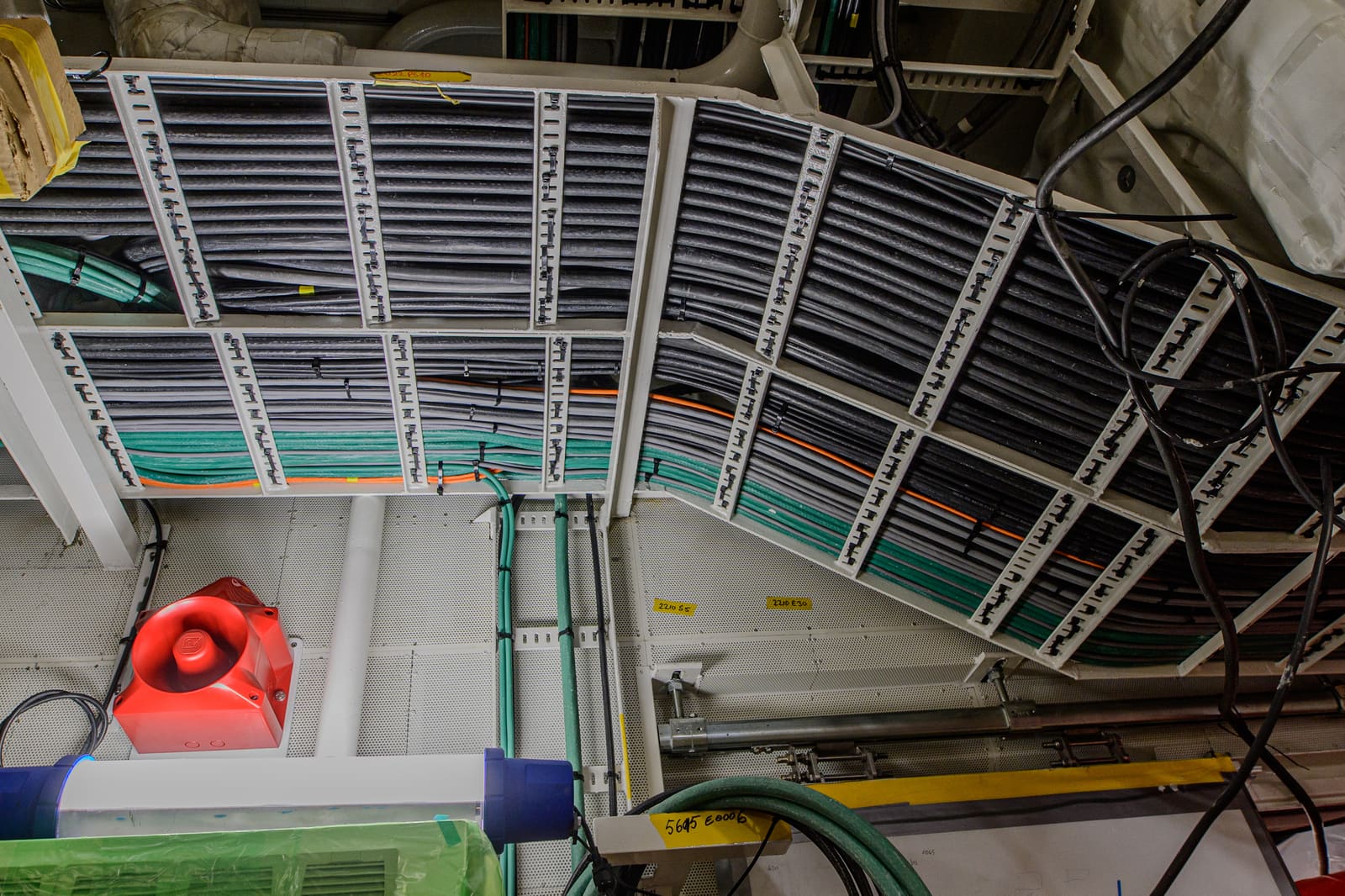 Overhead cable trays in a vessel compartment fully populated with bundled and tagged marine cables