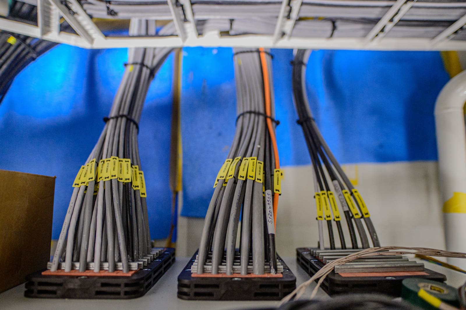 Marine cable bundles secured with cable ties through multi-cable transit blocks at a bulkhead penetration