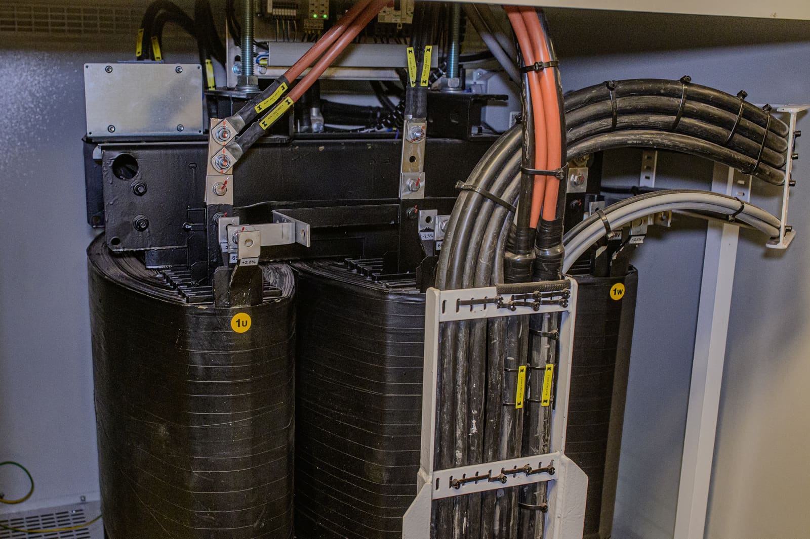 Pad-mounted transformer cable connection with marine power cables routed from primary core terminations down through a cable transit