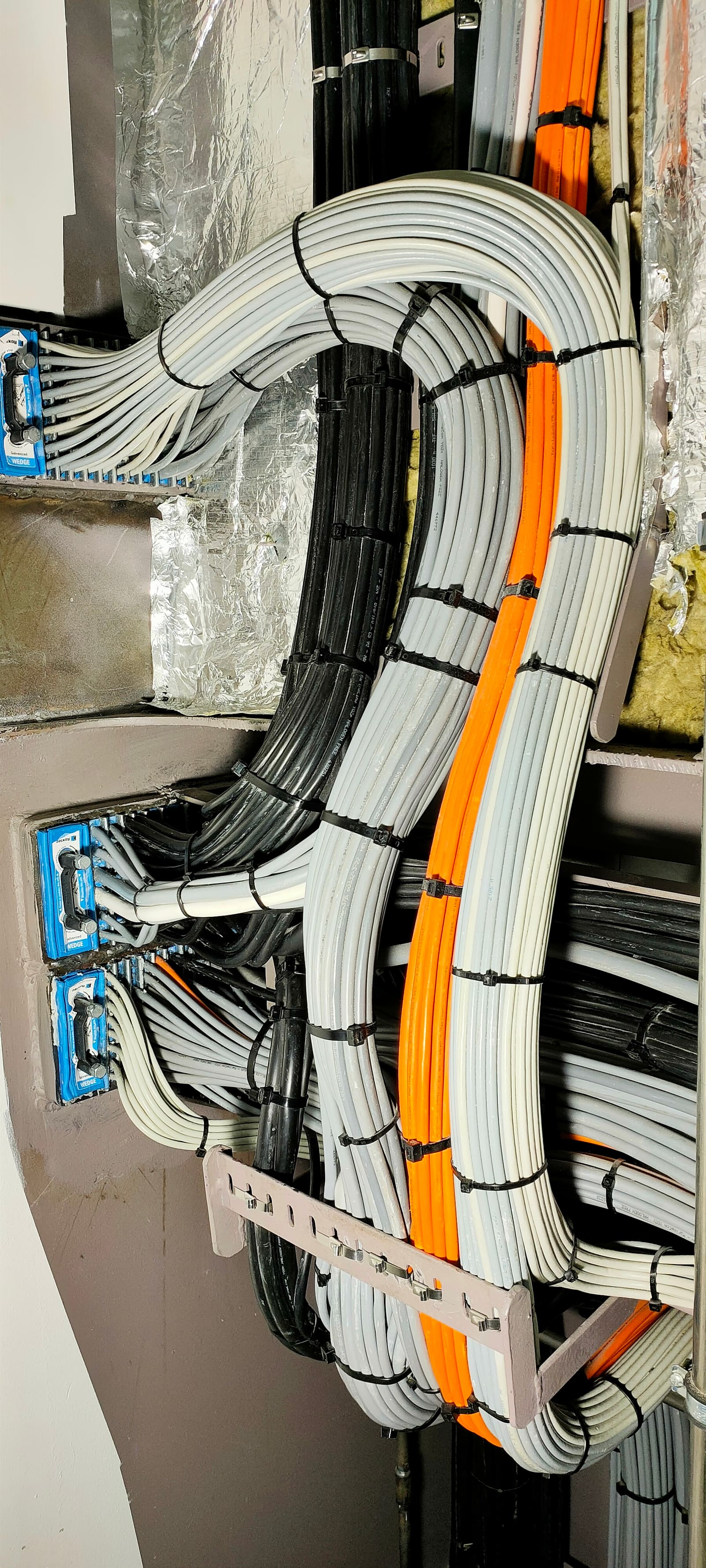 Vertical multi-transit bulkhead penetration with grey, orange and black marine cable bundles curving up between three transit blocks
