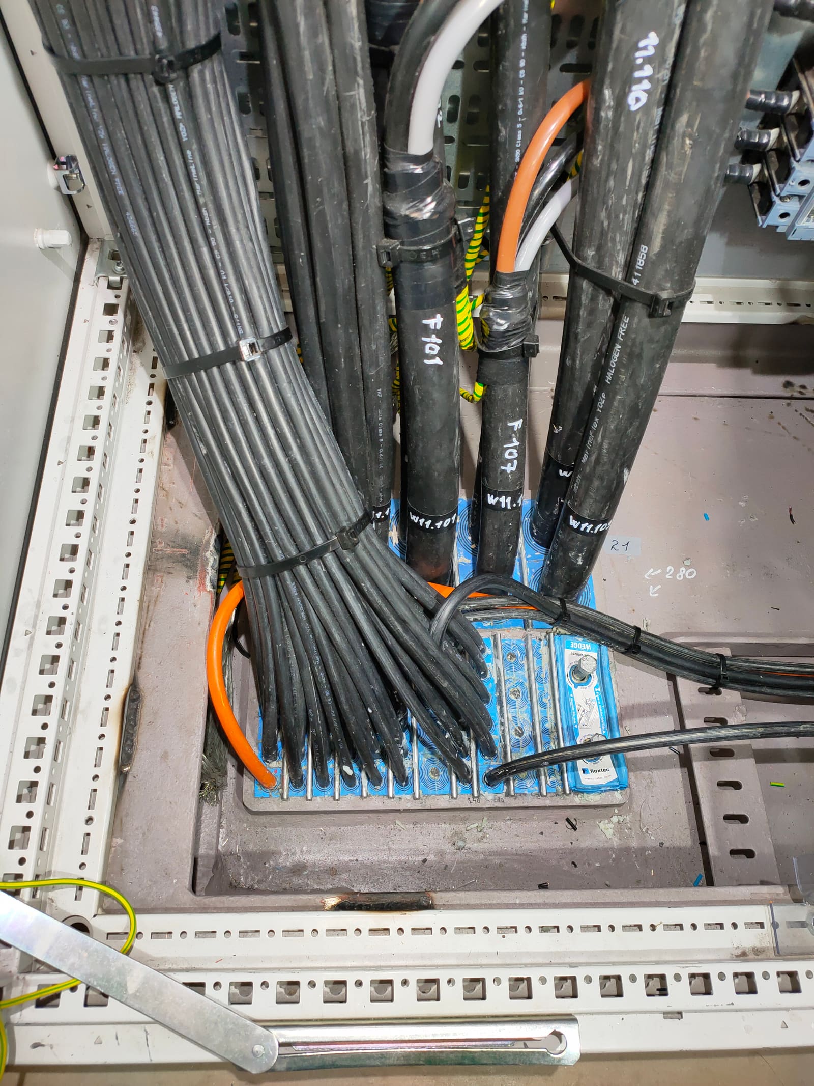 Heavy marine power cables labelled P-101, P-107 and P-110 entering the bottom of a switchboard through a multi-cable transit