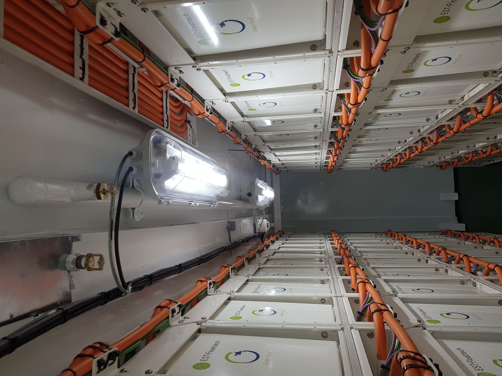 Battery rack room overhead view with orange interconnect cables linking lithium-ion battery modules in a marine ESS installation