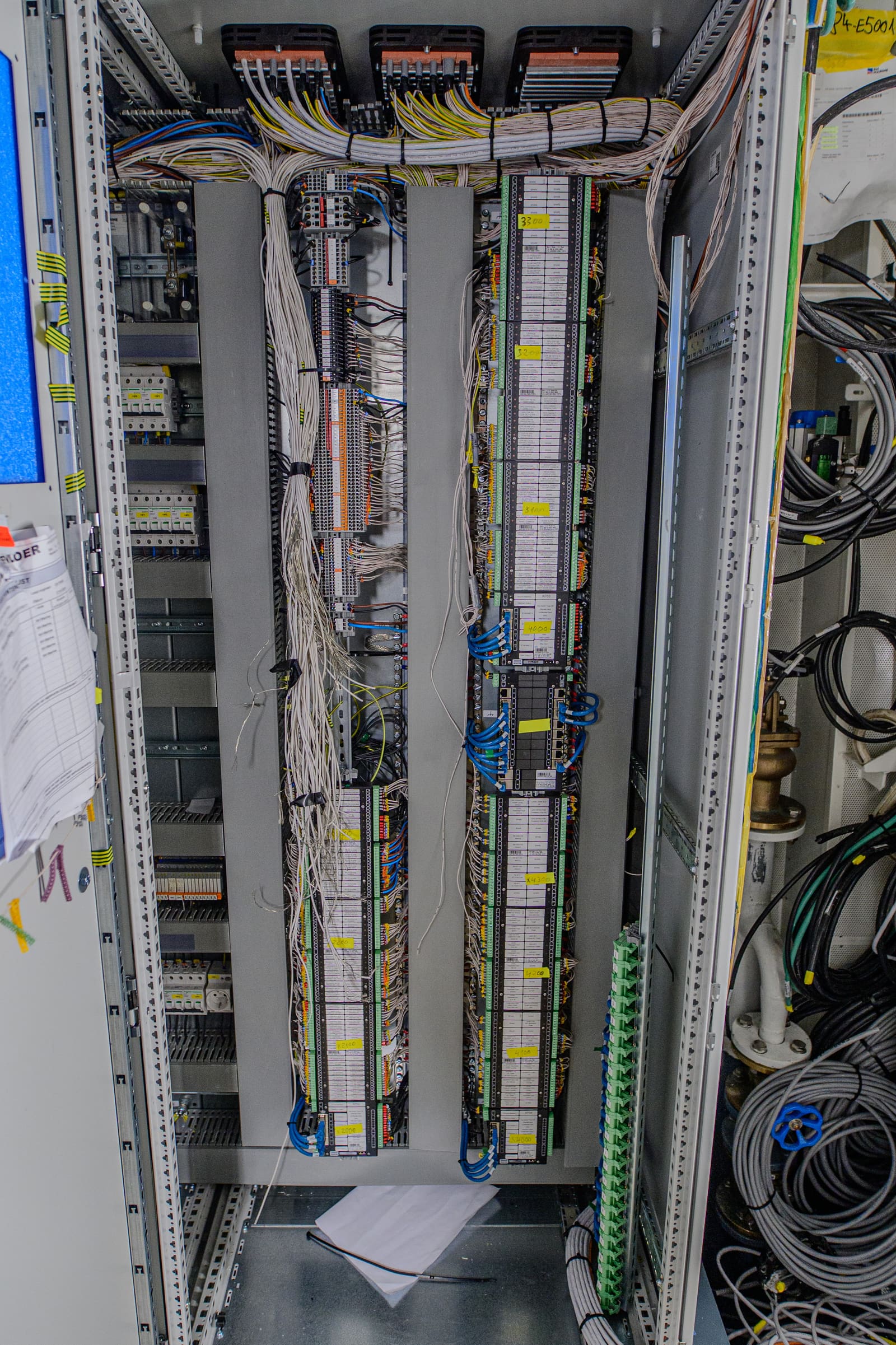 PLC marshalling cabinet interior with sorted and labelled signal cables landed on multi-level terminal strips across two vertical bays