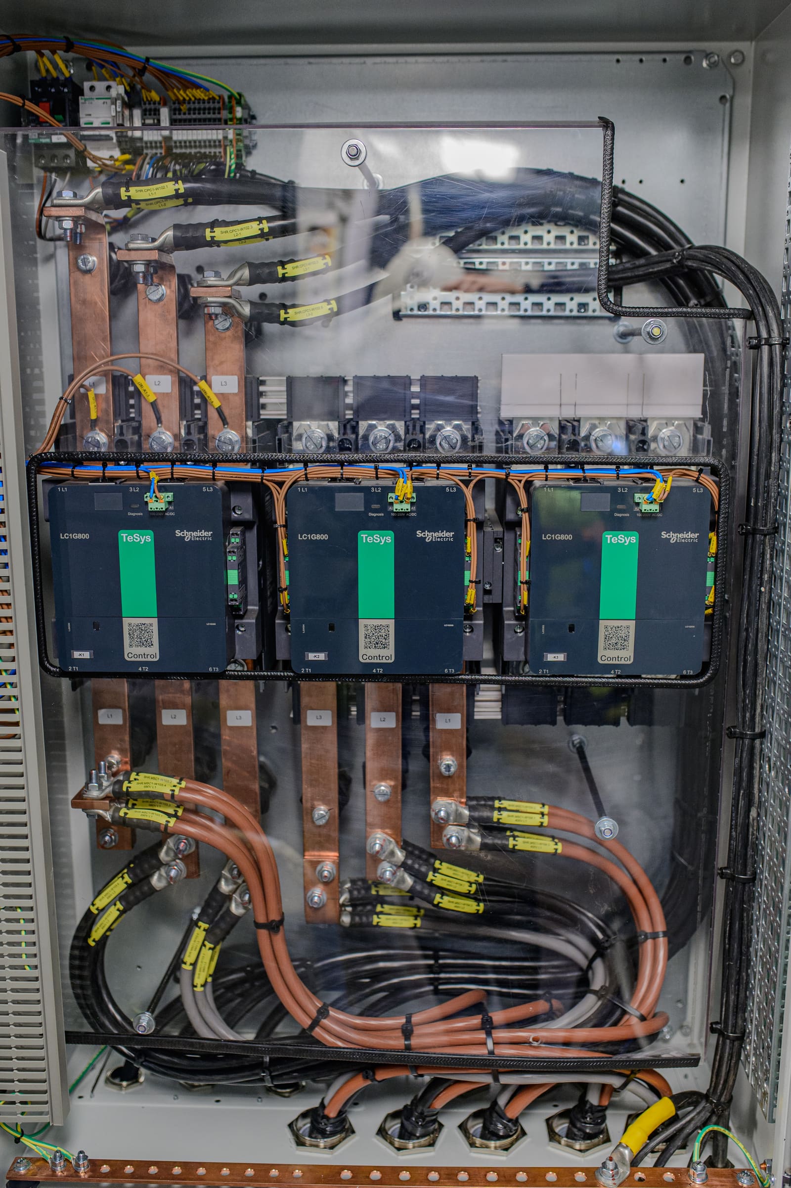 Motor starter cabinet with three Schneider TeSys motor starters fed by copper busbars and terminated outgoing motor cables