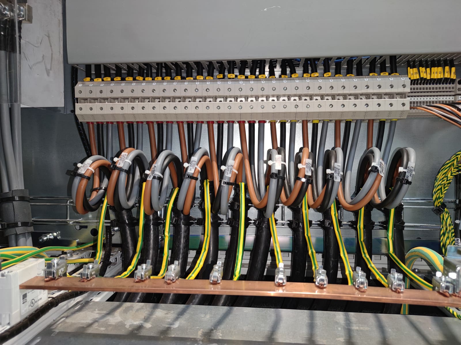 Distribution panel internals with multiple marine power cables terminated to outgoing breakers above a common grounding busbar