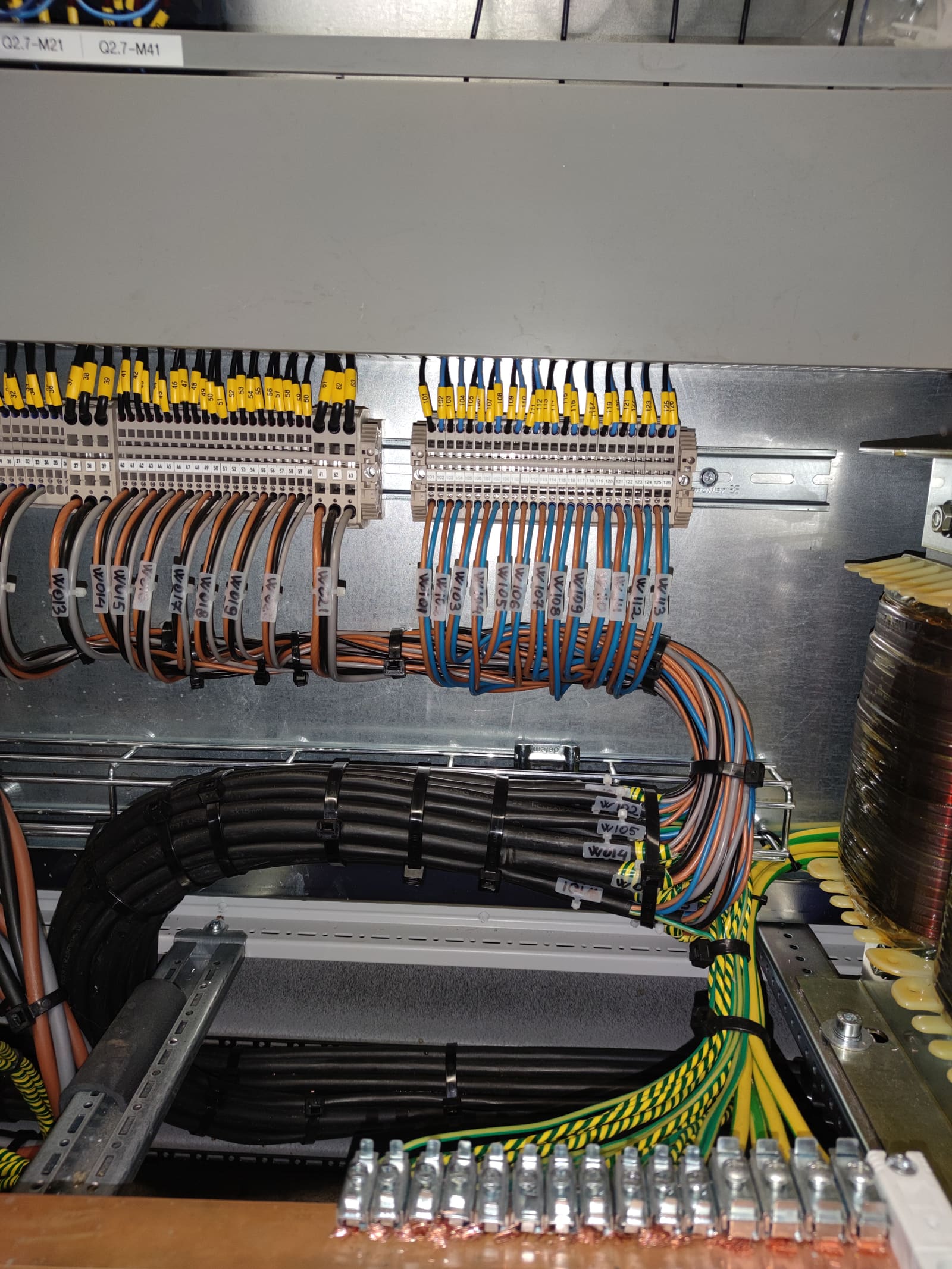 Marine PLC marshalling cabinet showing dressed terminations on numbered terminal blocks with grounding pigtails to a common busbar