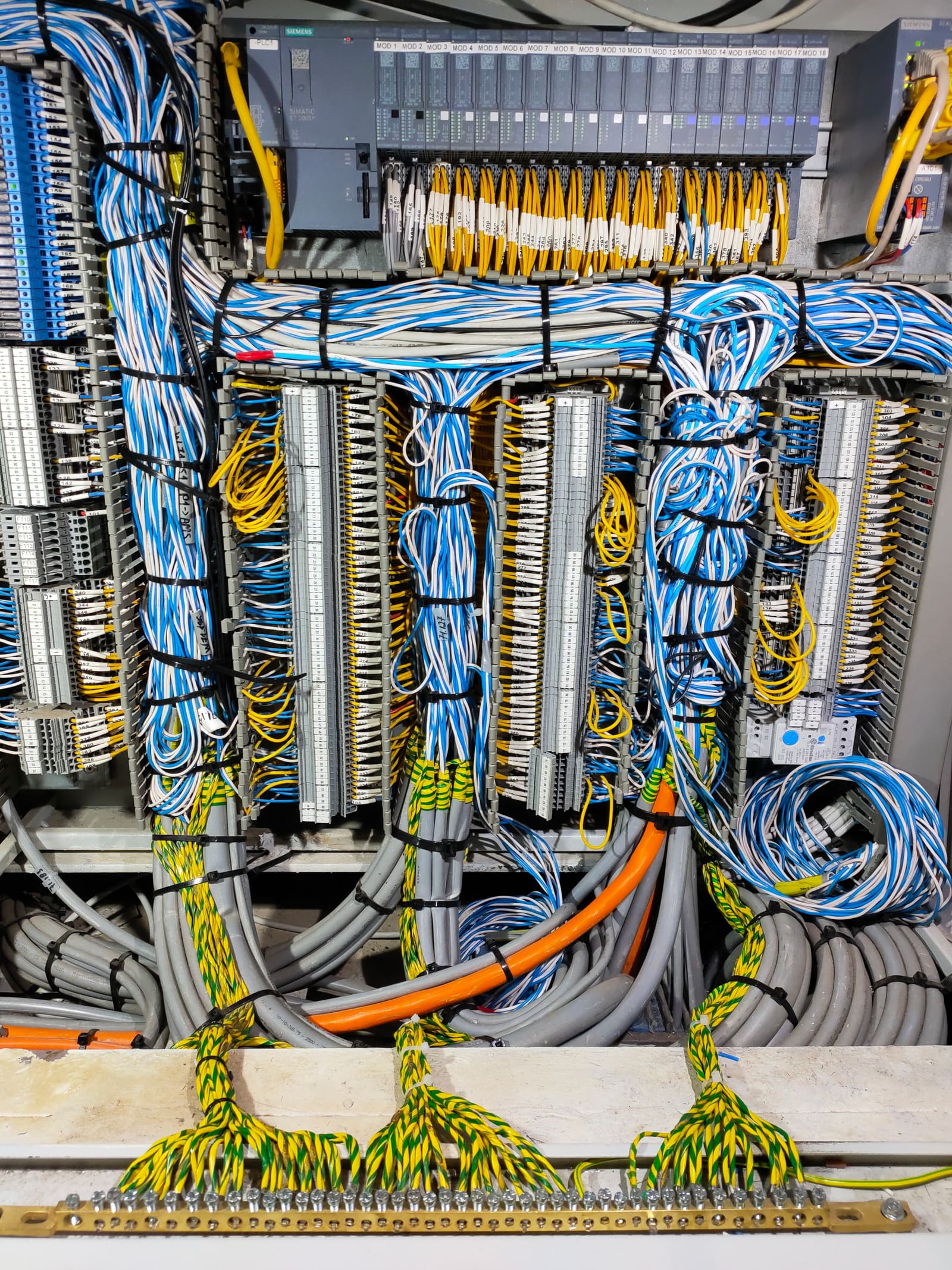 PLC IO marshalling cabinet with Siemens controller and dense yellow-and-blue signal cables terminated to multiple terminal block columns