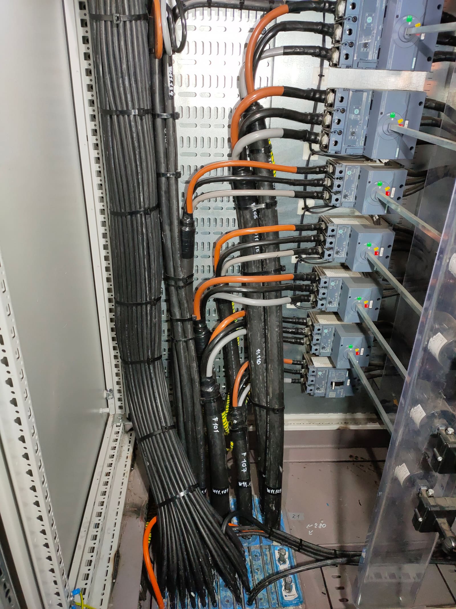 Distribution column with rows of Siemens MCCBs feeding outgoing marine power cables routed through perforated cable tray and labelled