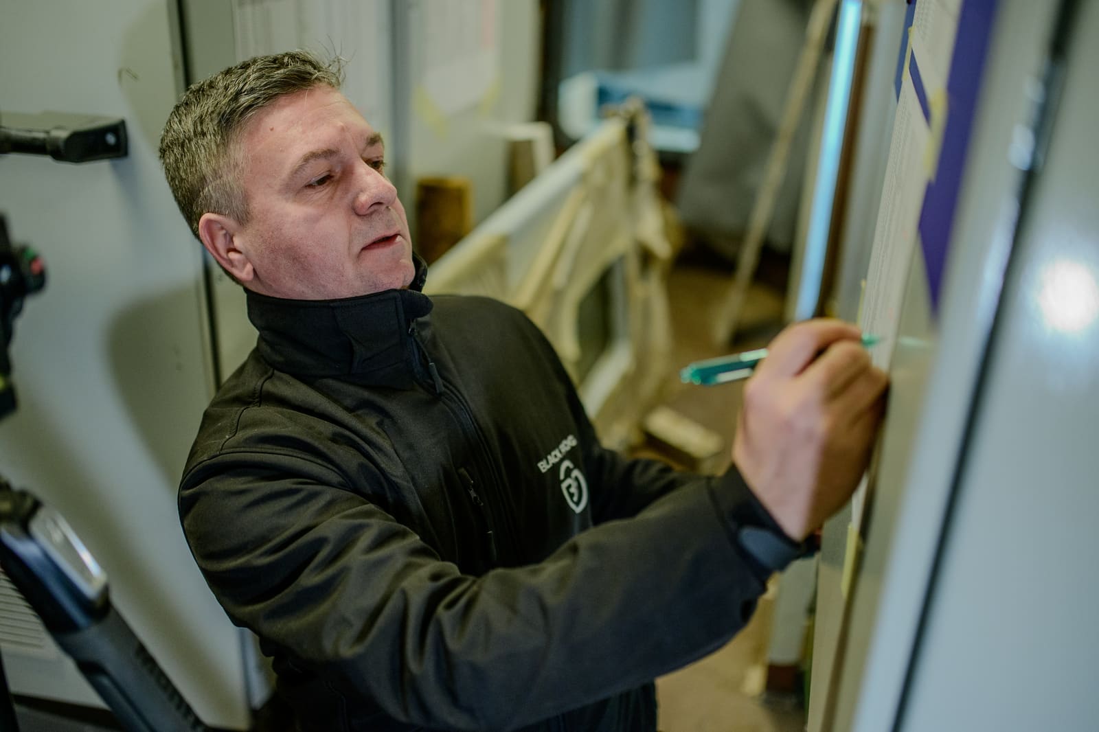 Senior commissioning engineer marking a wire on a test schedule pinned to a panel during pre-energisation checks