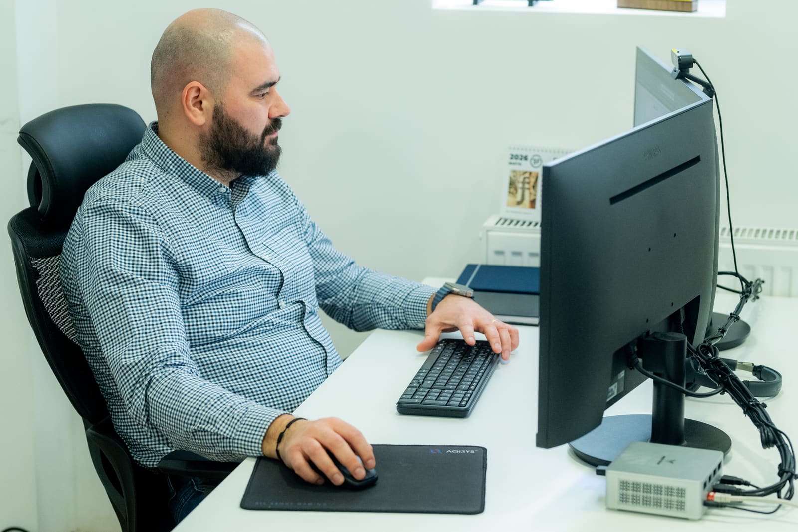 Senior procurement specialist reviewing supplier catalogs and pricing on his workstation at the Black Frog Elektro office