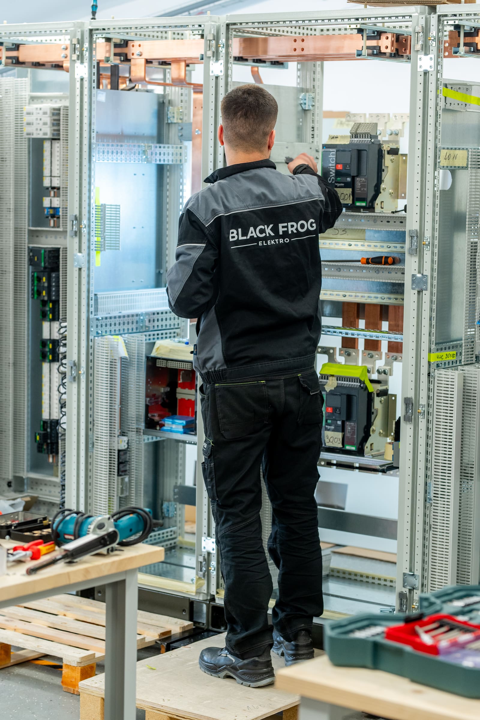 Black Frog Elektro panel builder in branded jacket fitting moulded-case circuit breakers onto a switchboard frame