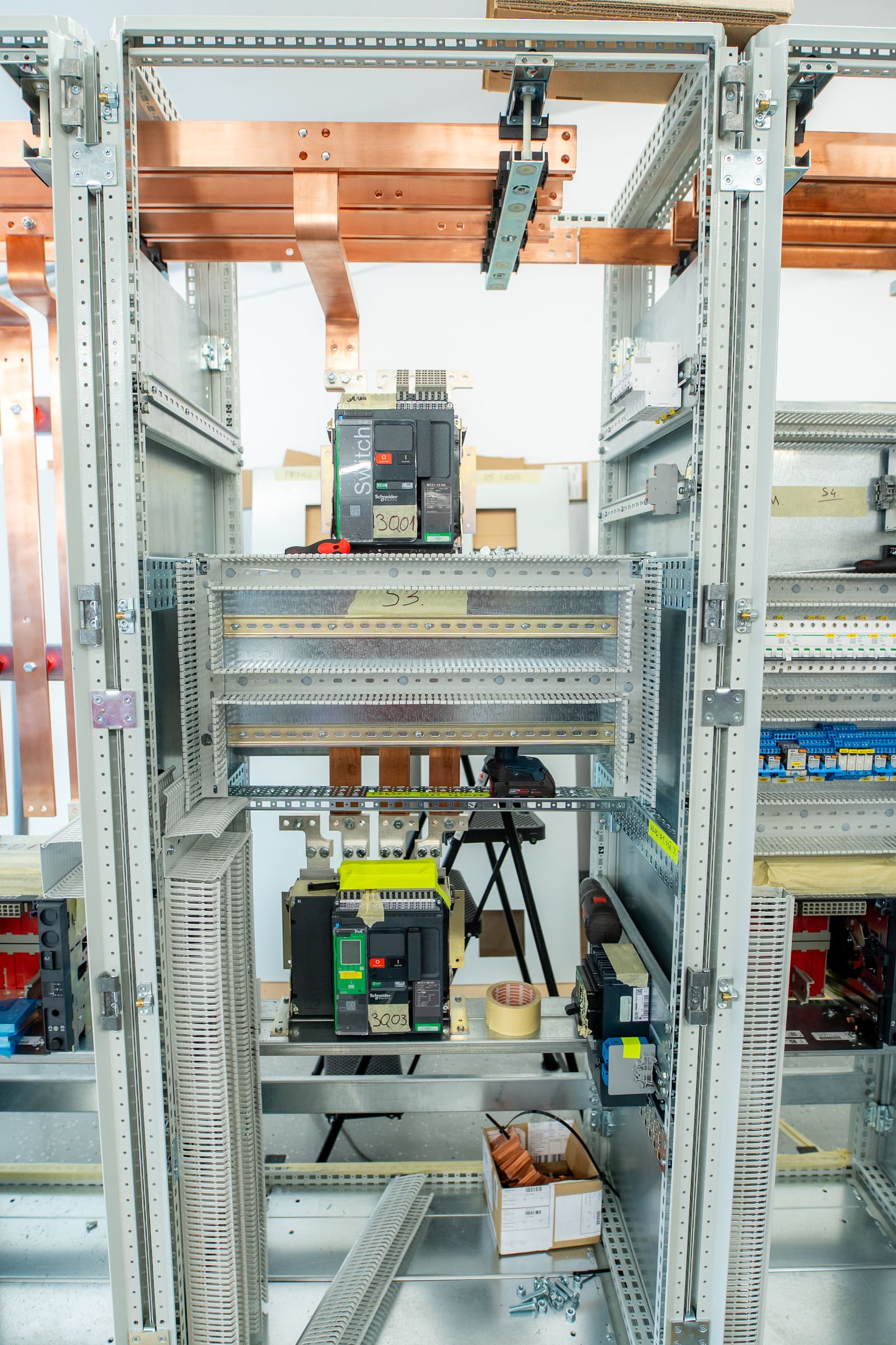 Empty Form 4 switchboard frame on the workshop floor with copper busbar system installed across the top and air-circuit breakers mounted