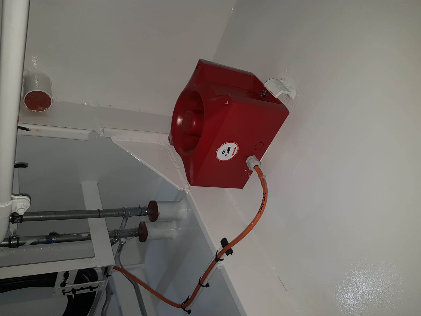 Marine sounder alarm and cabling installed at a deckhead corner near the firefighting piping