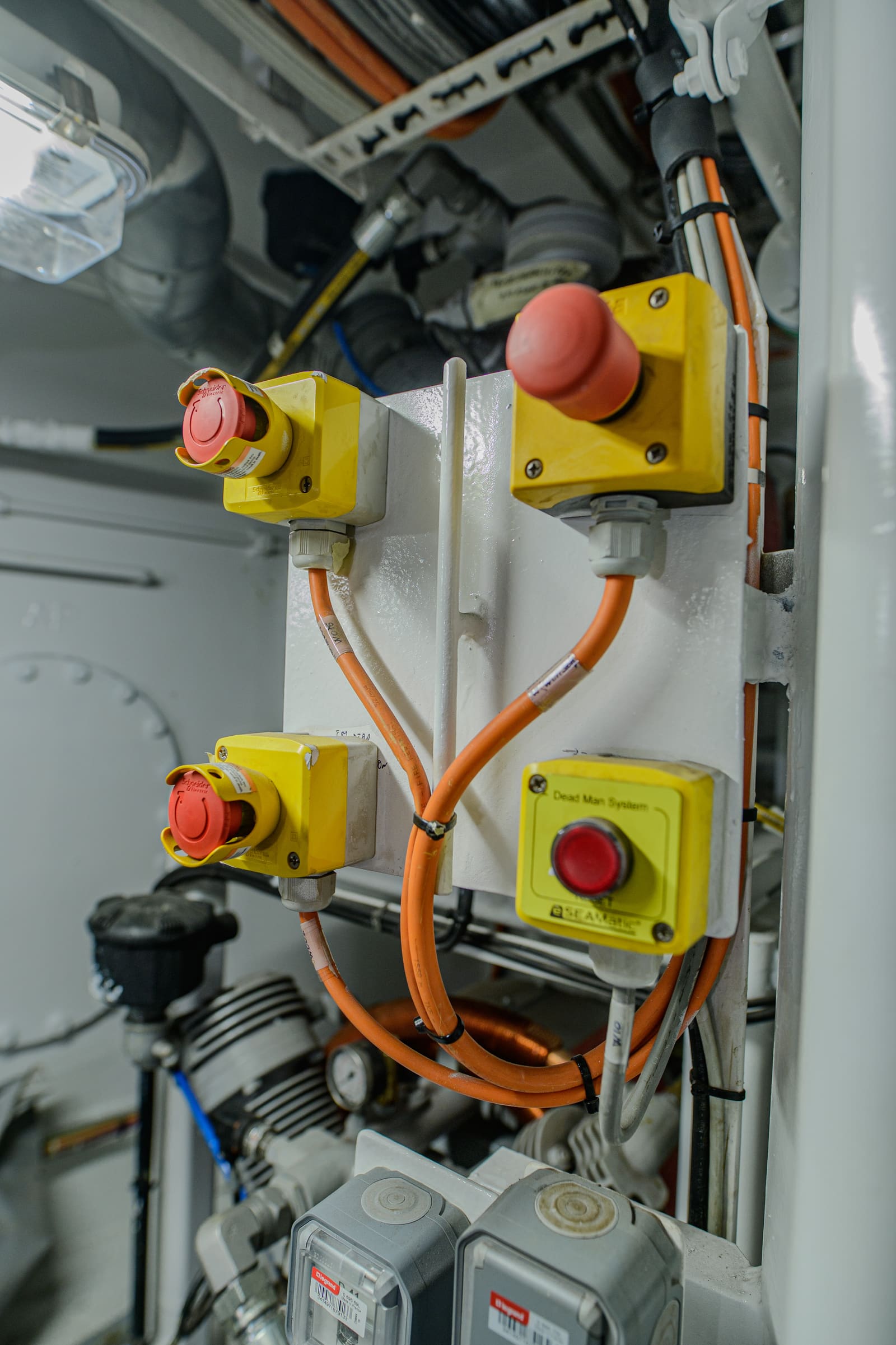 Engine-control panel with red emergency-stop and Dead Man System pushbuttons in IP65 yellow enclosures wired with orange marine cables