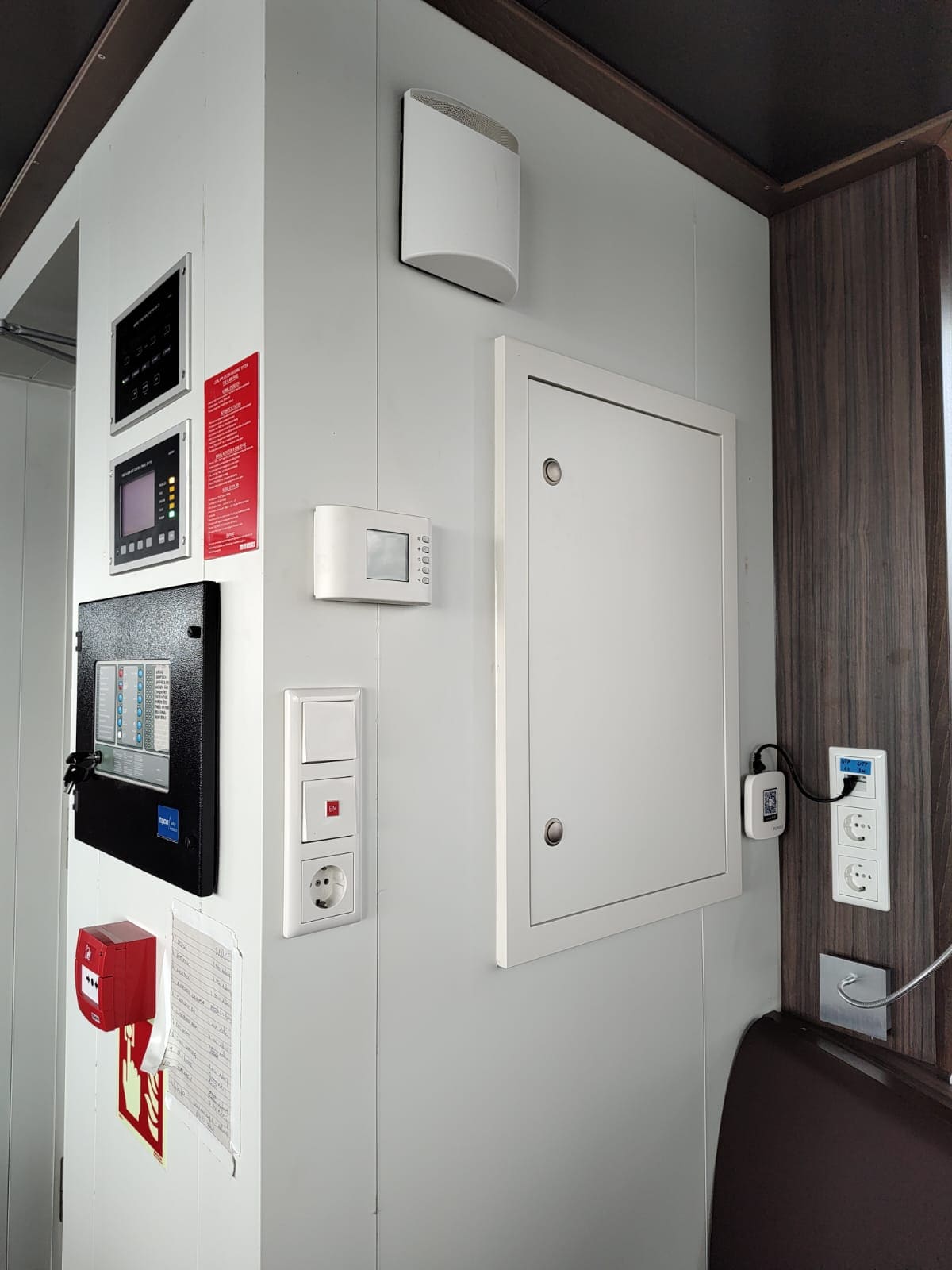 Cabin bulkhead with fire-detection control unit, climate control thermostat, distribution sub-board and combined power and data sockets installed